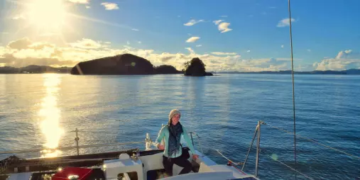 Woman enjoying a sunset sailing cruise with Barefoot Sailing Adventures in the Bay of Islands