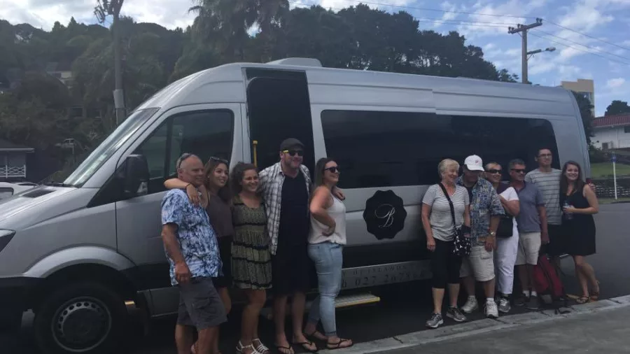 Tour group posing beside a Bay of Islands Tours van on a sunny day