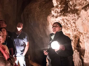 Guide holding a torch and leading a group through glow worm caves on a Bay of Islands tour