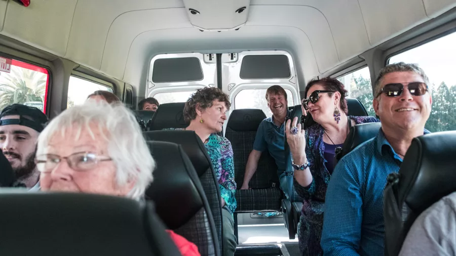 Passengers smiling and chatting inside a Bay of Islands Tours van during a shore excursion