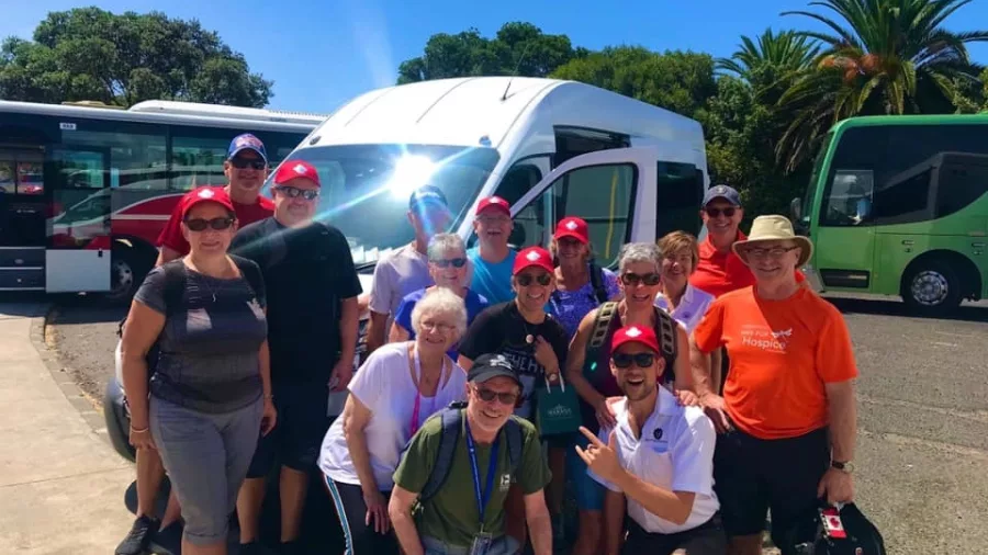 Cruise ship passengers posing with their guide Nick in front of a Bay of Islands Tours van
