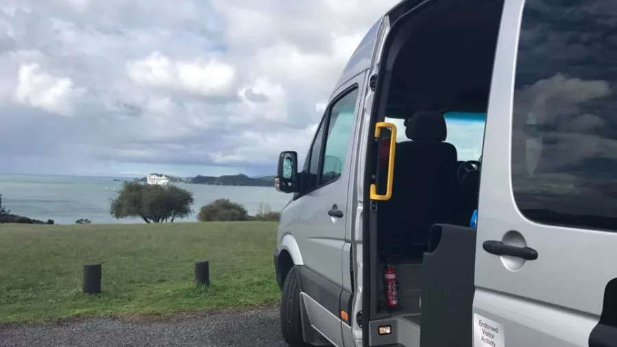 Bay of Islands Tours van parked at Waitangi with a cruise ship visible in the distance