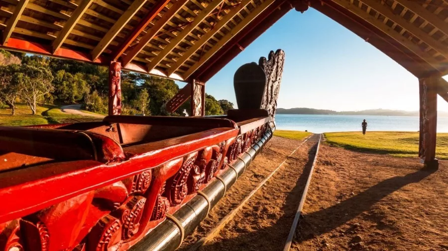 Traditional Māori waka housed at the Waitangi Treaty Grounds overlooking the water at sunrise