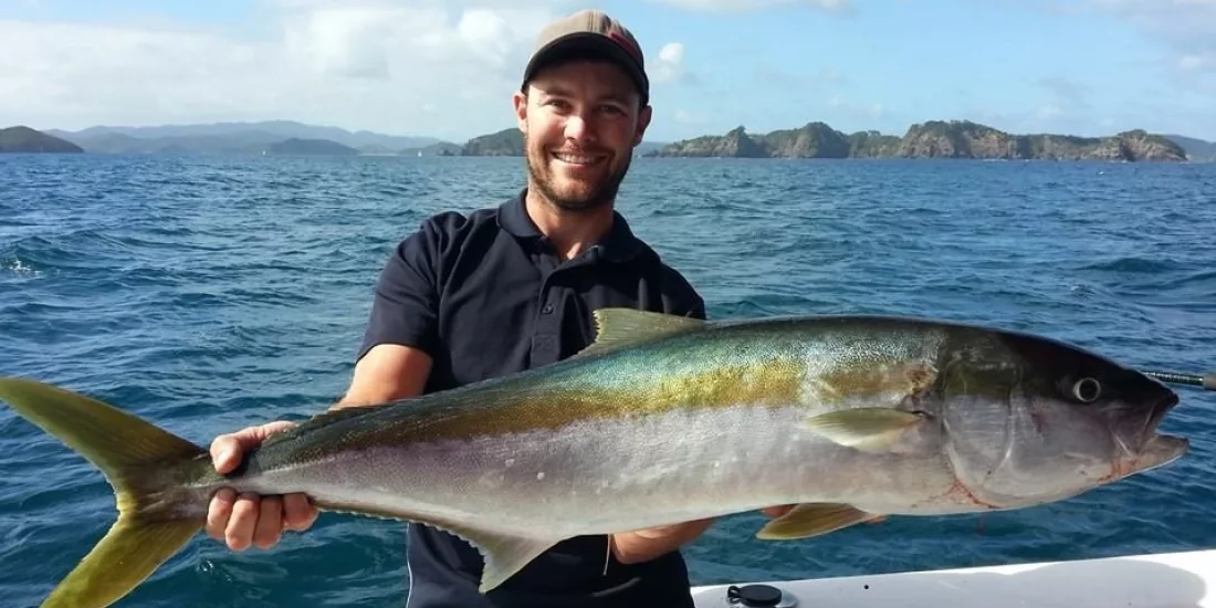 Man holding a large kingfish on a boat in the Bay of Islands, New Zealand