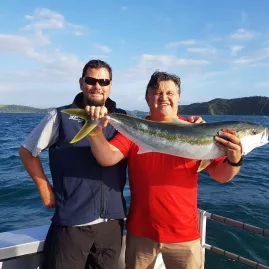 Man proudly holding a kingfish catch on a Bay of Islands fishing charter, New Zealand