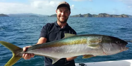 Man holding a large kingfish on a boat in the Bay of Islands, New Zealand