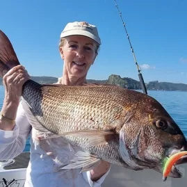 Woman holding a large snapper caught using a soft bait while fishing in the Bay of Islands