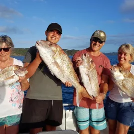 Four smiling people of different ages holding snapper on a fishing boat in the Bay of Islands