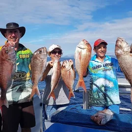 Family of three proudly holding six snapper fish on a sunny day in the Bay of Islands