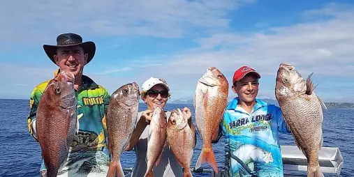 Family of three proudly holding six snapper fish on a sunny day in the Bay of Islands