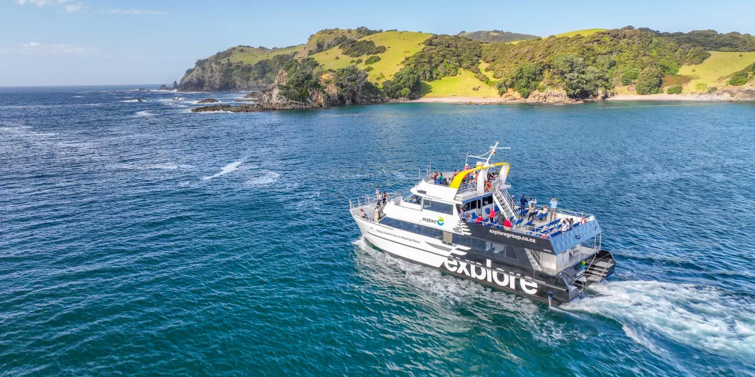 The Explore Group's Dolphin Seeker cruise boat sailing through the scenic waters of the Bay of Islands, offering passengers a chance to spot marine wildlife.