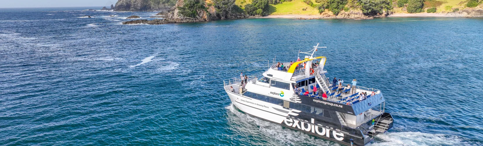The Explore Group's Dolphin Seeker cruise boat sailing through the scenic waters of the Bay of Islands, offering passengers a chance to spot marine wildlife.