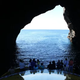 Passengers on a boat cruise experience the thrill of passing through the famous Hole in the Rock in the Bay of Islands, New Zealand.