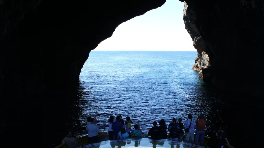 Passengers on a boat cruise experience the thrill of passing through the famous Hole in the Rock in the Bay of Islands, New Zealand.