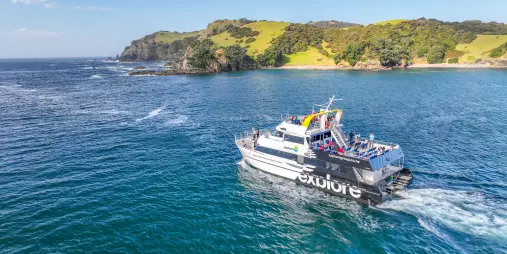 The Explore Group's Dolphin Seeker cruise boat sailing through the scenic waters of the Bay of Islands, offering passengers a chance to spot marine wildlife.
