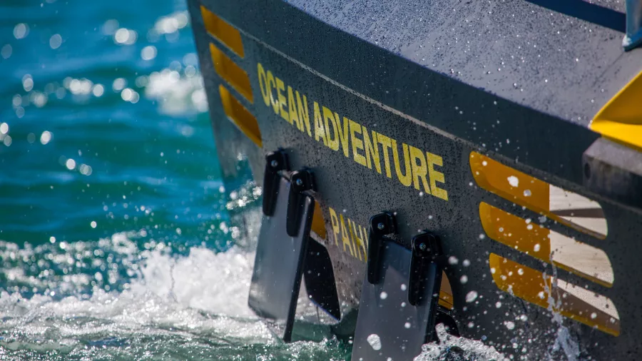 Close-up of the Ocean Adventure boat cruising through the waters, creating a splash, during a thrilling marine tour in New Zealand.