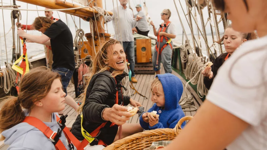 Children and crew members sharing fresh-baked scones aboard the R. Tucker Thompson sailing ship.