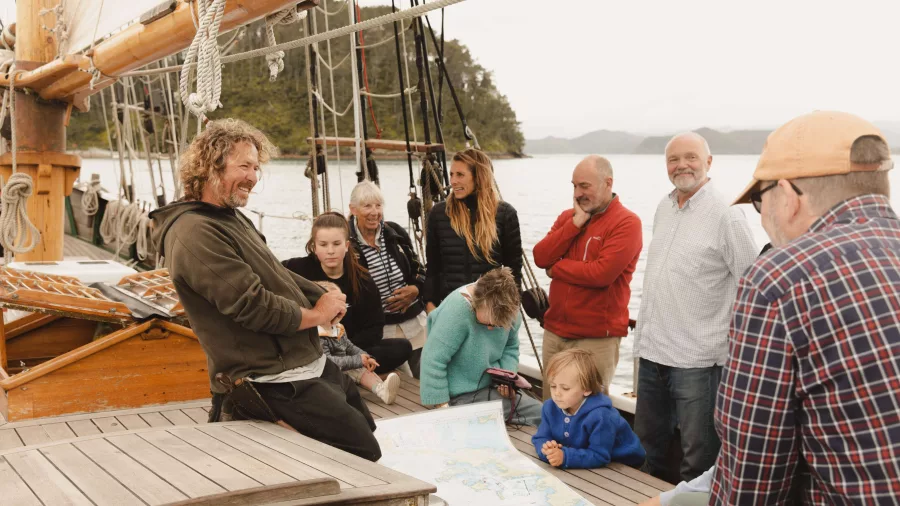 A group of passengers attentively listening to the captain share stories aboard the R. Tucker Thompson.