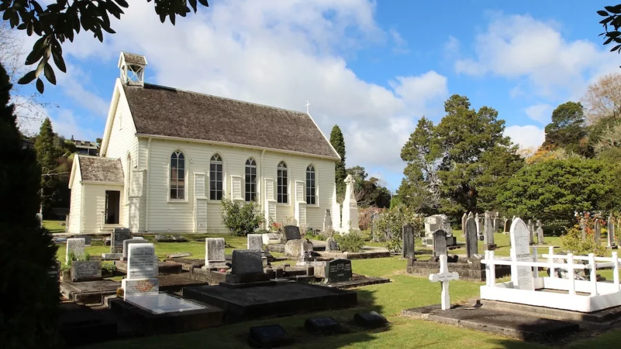 Christ's Church, a historic church with a peaceful graveyard, surrounded by lush greenery under a partly cloudy sky.