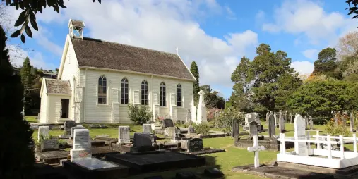 Christ's Church, a historic church with a peaceful graveyard, surrounded by lush greenery under a partly cloudy sky.