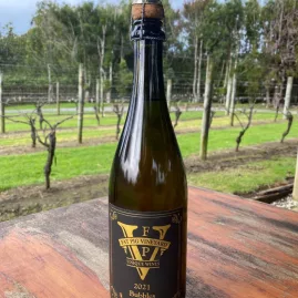 Bottle of 2021 Bubbles from Fat Pig Vineyard with vines in the background
