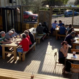 Groups of people enjoying drinks in a sunny beer garden in Kerikeri