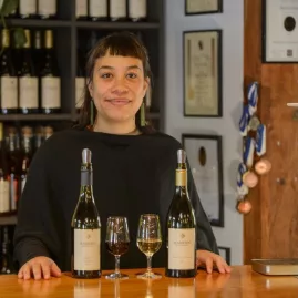 Smiling wine host standing behind two bottles and glasses at Marsden Estate cellar door