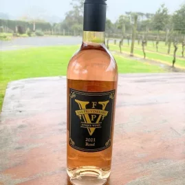2021 Rosé wine bottle from Fat Pig Vineyard on a wooden table with vineyard background