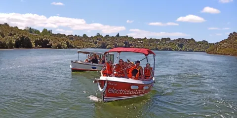 Group enjoying an electric boat ride in Kerikeri on a sunny day