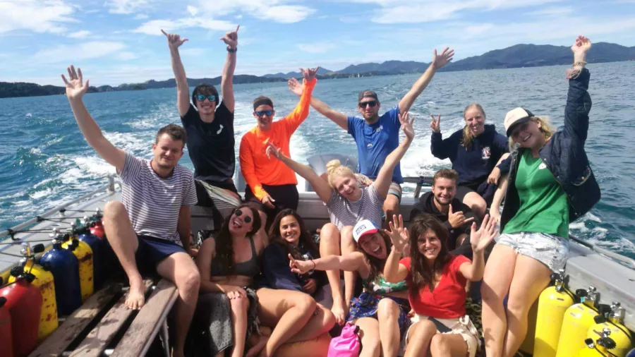 Group of people smiling and posing on a dive boat in the Bay of Islands during a Discovery Scuba trip