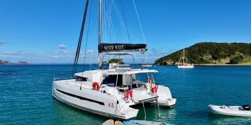 Silver Wave catamaran anchored near Waewaetorea Island with paddleboards floating behind