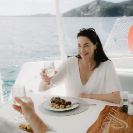 Couple enjoying lunch with white wine on a catamaran