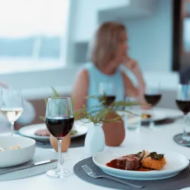 Dinner party on a catamaran with gourmet meals and wine served on a stylish table setting