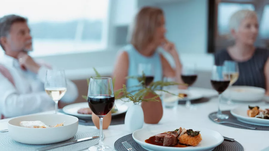 Dinner party on a catamaran with gourmet meals and wine served on a stylish table setting