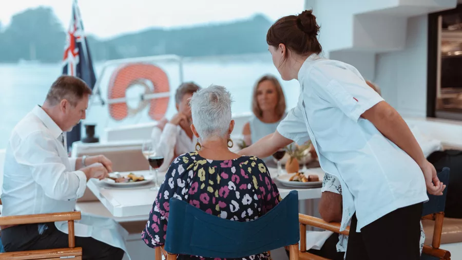 Guests enjoying a dinner service on the deck of Silver Wave Yacht with wine and plated meals