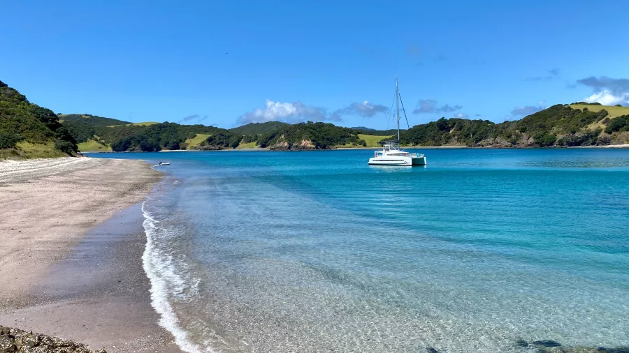 Quiet shoreline and anchored yacht at South Waewaetorea Beach in the Bay of Islands