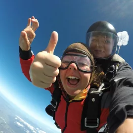 Eloise giving a thumbs up during a tandem skydive at 9000 feet above Northland