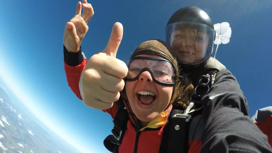 Eloise giving a thumbs up during a tandem skydive at 9000 feet above Northland