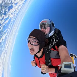 Tandem skydiving with wide smile and tilted horizon over Bay of Islands