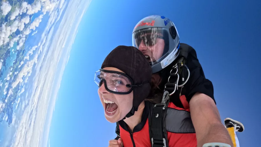 Tandem skydiving with wide smile and tilted horizon over Bay of Islands
