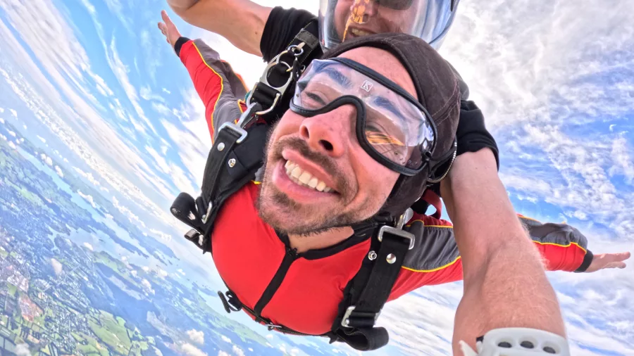 Man tandem skydiving with big smile above scenic Bay of Islands