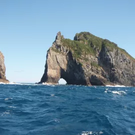 Hole in the Rock formation rising from the sea in the Bay of Islands