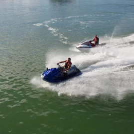 Two people riding jet skis side by side in the Bay of Islands