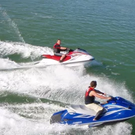 Two people riding jet skis side by side in the Bay of Islands