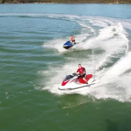 Two people riding jet skis on clear green water in the Bay of Islands