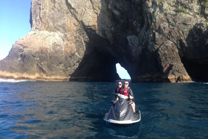 Jet-ski passing through the Hole in the Rock along New Zealand’s Whakaari/White Island coast