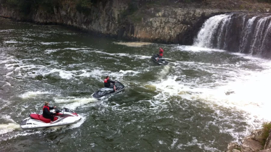 Jet skis floating near the base of Haruru Falls in the Bay of Islands