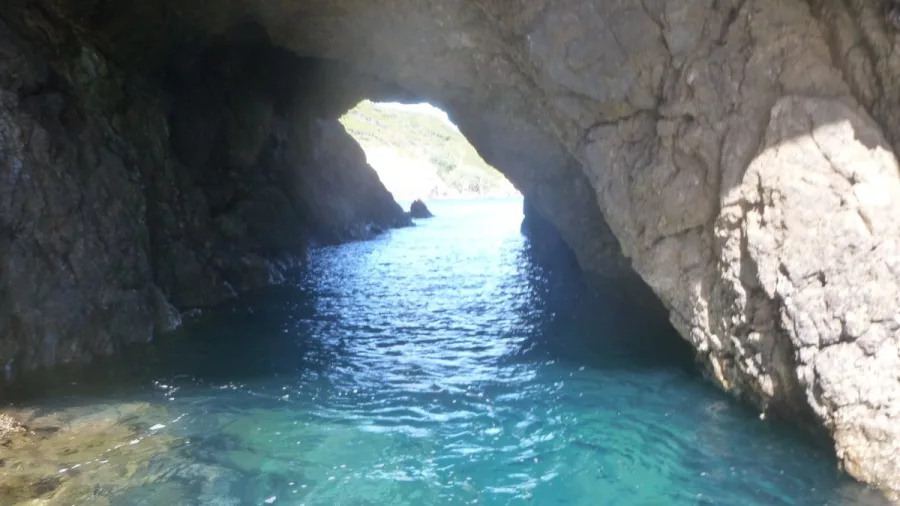 View from inside a sea cave looking out to clear blue waters in the Bay of Islands
