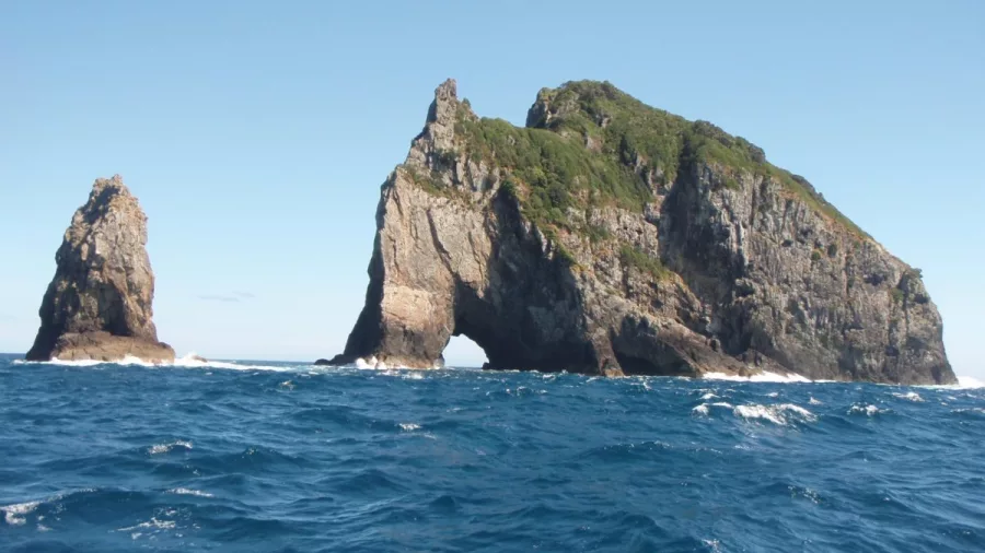 Hole in the Rock formation rising from the sea in the Bay of Islands
