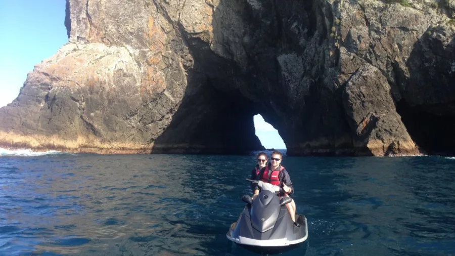 Jet-ski passing through the Hole in the Rock along New Zealand’s Whakaari/White Island coast